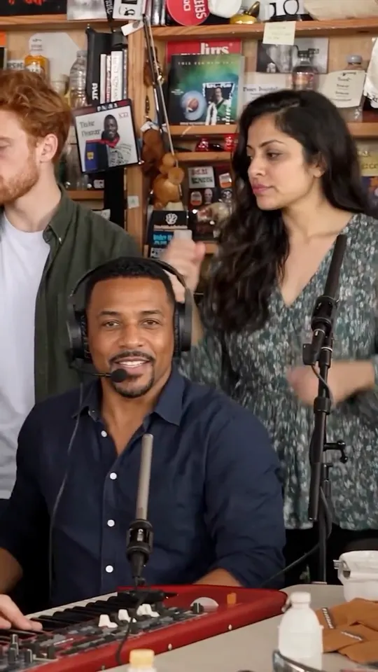 Opening group shot with three backing performers at the desk